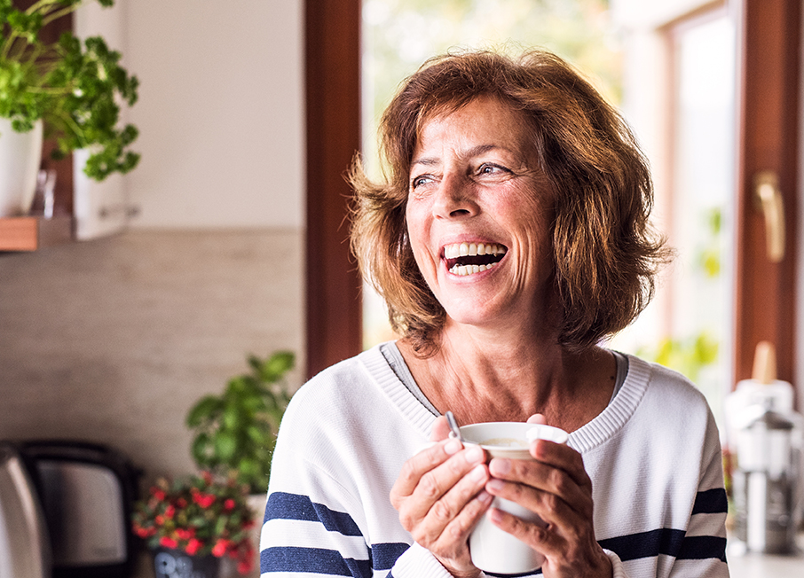 Woman holding a beverage looking outside window