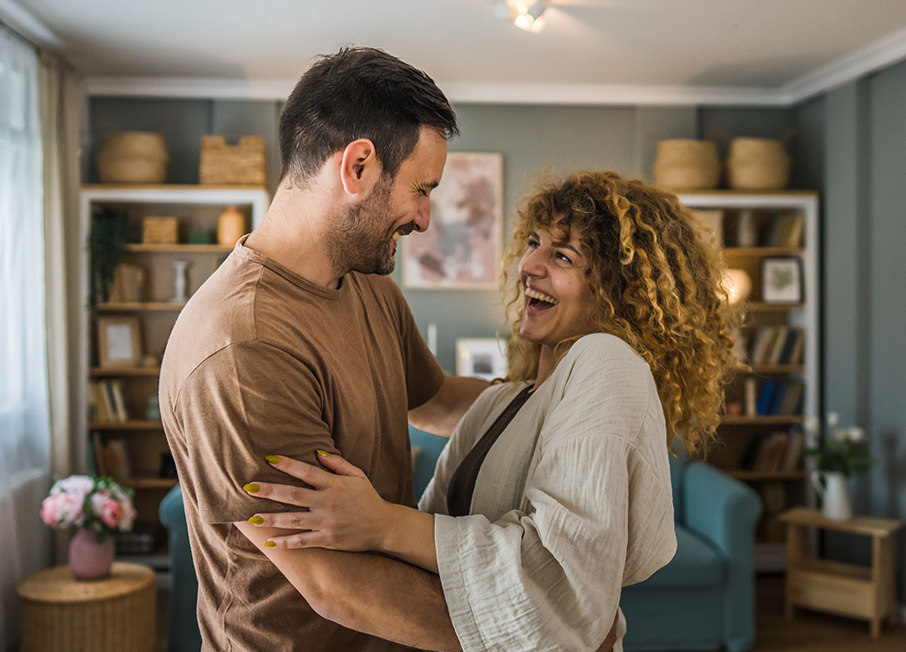 Happy couple standing and hugging in living room