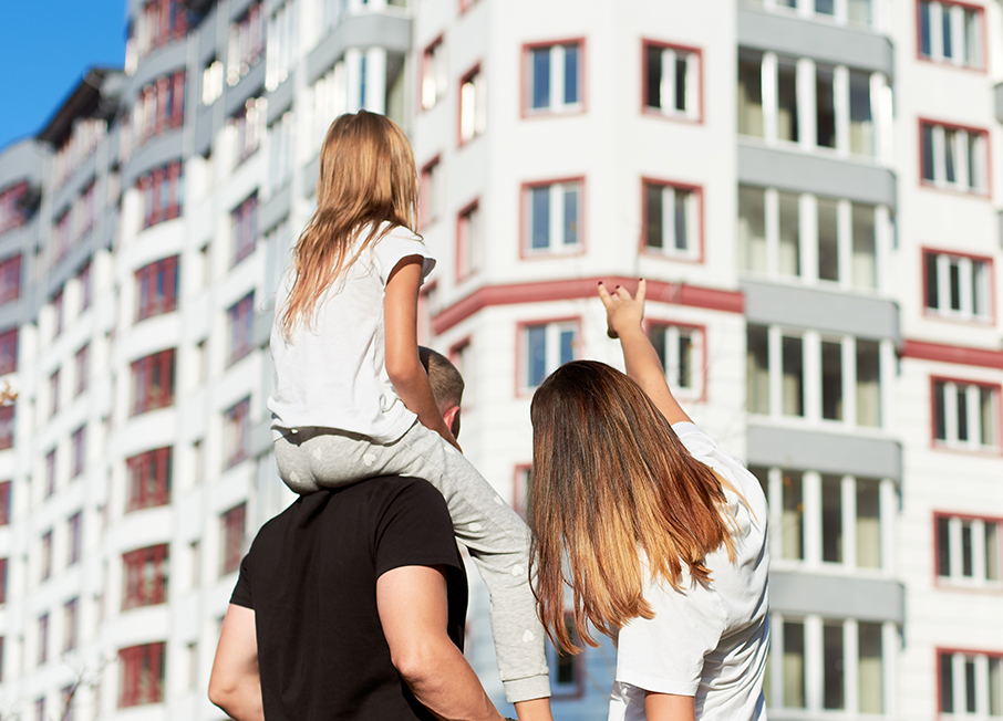 Couple with child looking at apartment block buildings